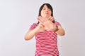 Young beautiful chinese woman wearing red striped t-shirt over isolated white background Rejection expression crossing arms and Royalty Free Stock Photo