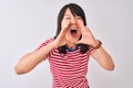 Young beautiful chinese woman wearing red striped t-shirt over isolated white background Shouting angry out loud with hands over Royalty Free Stock Photo