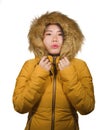 Young beautiful and cool Asian Japanese woman posing in Winter weather wearing yellow jacket with fur hood isolated on studio Royalty Free Stock Photo