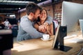 Blurred faces of young man and woman colleagues talking in front of table with desktop computer, in clothing store Royalty Free Stock Photo