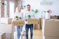 Young beautiful couple with dog moving cardboard boxes at new home Royalty Free Stock Photo