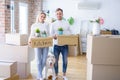 Young beautiful couple with dog moving cardboard boxes at new home Royalty Free Stock Photo