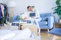 Young beautiful couple with dog sitting on the sofa holding blackboard with message kissing at new home around cardboard boxes Royalty Free Stock Photo