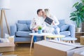 Young beautiful couple with dog sitting on the sofa holding blackboard with message kissing at new home around cardboard boxes Royalty Free Stock Photo