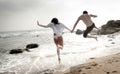 Young beautiful couple having fun jumping along beach Royalty Free Stock Photo