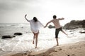 Young beautiful couple having fun jumping along beach Royalty Free Stock Photo