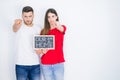 Young beautiful couple holding blackboard with new home text over white isolated background pointing with finger to the camera and Royalty Free Stock Photo