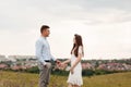 Young beautiful couple holding hands and looking at each other in the field in summer. woman with long hair and a man with a Royalty Free Stock Photo
