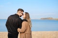 Young beautiful couple hugging on the beach during the cold season in sunny weather Royalty Free Stock Photo