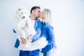 Young beautiful couple kissing holding dog standing over isolated white background Royalty Free Stock Photo