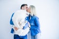 Young beautiful couple kissing holding dog standing over isolated white background Royalty Free Stock Photo