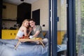 Young beautiful couple in love is sitting in bed and having healthy breakfast together. Royalty Free Stock Photo