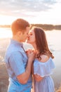 Young beautiful couple in love staying and kissing on the beach on sunset. Soft sunny colors. Royalty Free Stock Photo