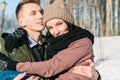 Young beautiful couple in love walking in a winter snowy park on a bright sunny day. Young man holds his beloved girl in his arms Royalty Free Stock Photo