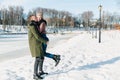 Young beautiful couple in love walking in a winter snowy park on a bright sunny day Royalty Free Stock Photo