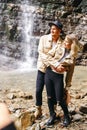 Young and beautiful couple at the mountain waterfall - Happy tourists visiting mountains. Lovestory. Tourists in hats. Military