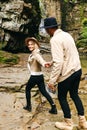 Young and beautiful couple at the mountain waterfall - Happy tourists visiting mountains. Lovestory. Tourists in hats. Military