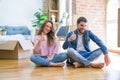 Young beautiful couple moving to a new house sitting on the floor doing happy thumbs up gesture with hand Royalty Free Stock Photo