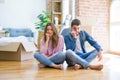 Young beautiful couple moving to a new house sitting on the floor looking stressed and nervous with hands on mouth biting nails Royalty Free Stock Photo