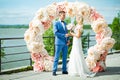 Young beautiful couple of newlyweds bride and groom during a wedding ceremony on the beach near the large arch dress rings. Love Royalty Free Stock Photo