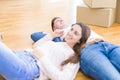 Young beautiful couple relaxing lying on the floor around cardboard boxes at home, smiling happy moving to a new house Royalty Free Stock Photo