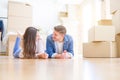 Young beautiful couple relaxing lying on the floor around cardboard boxes at home, smiling happy moving to a new house Royalty Free Stock Photo