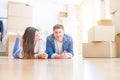 Young beautiful couple relaxing lying on the floor around cardboard boxes at home, smiling happy moving to a new house Royalty Free Stock Photo