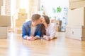 Young beautiful couple relaxing lying on the floor around cardboard boxes at home, smiling happy moving to a new house Royalty Free Stock Photo