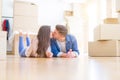 Young beautiful couple relaxing lying on the floor around cardboard boxes at home, smiling happy moving to a new house Royalty Free Stock Photo