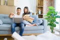 Young beautiful couple relaxing sitting on the sofa of new house using computer laptop very happy pointing with hand and finger Royalty Free Stock Photo
