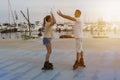 Young beautiful couple roller skating ,giving high five two hands at sunset in skate park next to the port in summer.Friendship Royalty Free Stock Photo