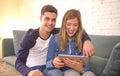 Young beautiful couple 20s using digital tablet pad computer sitting at home couch living room shopping on line choosing items on Royalty Free Stock Photo