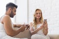 Young Beautiful Couple Sit On Coach Near Window, Using Cell Smart Phone Happy Smile Hispanic Man Woman Royalty Free Stock Photo