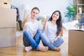 Young beautiful couple sitting on the floor at new home around cardboard boxes doing happy thumbs up gesture with hand Royalty Free Stock Photo