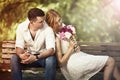 Young beautiful couple sitting in the park and man proposing wo