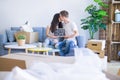 Young beautiful couple sitting on the sofa holding blackboard with message at new home around cardboard boxes Royalty Free Stock Photo