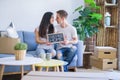 Young beautiful couple sitting on the sofa holding blackboard with message at new home around cardboard boxes Royalty Free Stock Photo