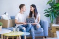 Young beautiful couple sitting on the sofa holding blackboard with message at new home around cardboard boxes Royalty Free Stock Photo