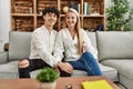 Young beautiful couple sitting on the sofa at home looking positive and happy standing and smiling with a confident smile showing Royalty Free Stock Photo