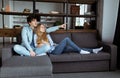 Young beautiful couple sitting on the sofa watching TV together Royalty Free Stock Photo