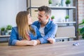 Young beautiful couple sitting on the table at home, hugging in love very happy for moving to new home with cardboard boxes behind Royalty Free Stock Photo