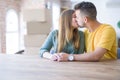 Young beautiful couple sitting on the table at home, hugging in love very happy for moving to new home with cardboard boxes behind Royalty Free Stock Photo