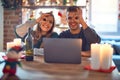 Young beautiful couple sitting using laptop around christmas decoration at home doing ok gesture with hand smiling, eye looking Royalty Free Stock Photo