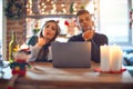 Young beautiful couple sitting using laptop around christmas decoration at home looking at the camera blowing a kiss with hand on Royalty Free Stock Photo