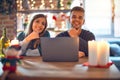 Young beautiful couple sitting using laptop around christmas decoration at home looking confident at the camera smiling with Royalty Free Stock Photo