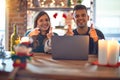 Young beautiful couple sitting using laptop around christmas decoration at home pointing fingers to camera with happy and funny Royalty Free Stock Photo