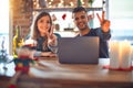 Young beautiful couple sitting using laptop around christmas decoration at home smiling looking to the camera showing fingers Royalty Free Stock Photo