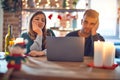 Young beautiful couple sitting using laptop around christmas decoration at home thinking looking tired and bored with depression Royalty Free Stock Photo