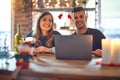 Young beautiful couple sitting using laptop around christmas decoration at home winking looking at the camera with sexy Royalty Free Stock Photo