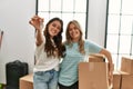 Young beautiful couple smiling happy holding cardboard box and key of new home Royalty Free Stock Photo